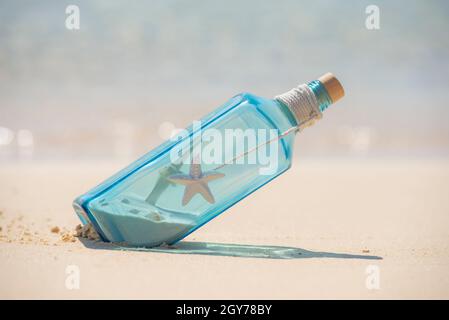 Gros plan de verre bleu encore la vie sur l'île tropicale sable plage paradis avec l'océan en arrière-plan concept message dans une bouteille Banque D'Images