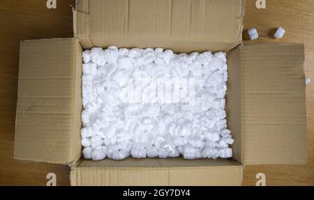 Une boîte en carton avec mousse d'emballage vue de dessus, boîte de livraison pour les produits fragiles sur table de copie en bois Banque D'Images