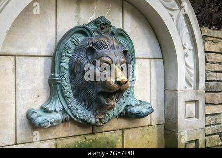 Fontaine à la tête du lion sur le mur. Texture murale en briques vintage avec stuc en forme de lion. La face moulée d'un lion est vaporisée d'eau. Bas-relief lion f Banque D'Images