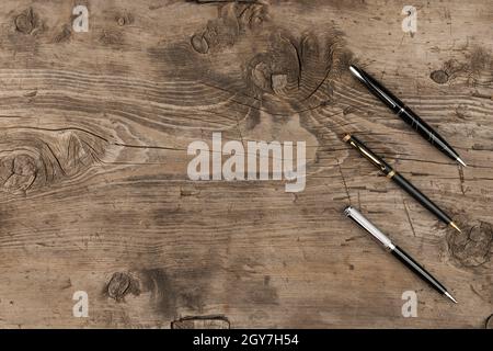 Stylos noir, or et argent sur une texture en bois, avec place pour votre texte Banque D'Images