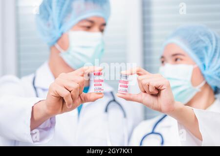 Jeune femme médecin ou scientifique en uniforme portant un masque facial montrant le vaccin du coronavirus, infirmière tenant une bouteille de vaccin COVID-19 à labora Banque D'Images