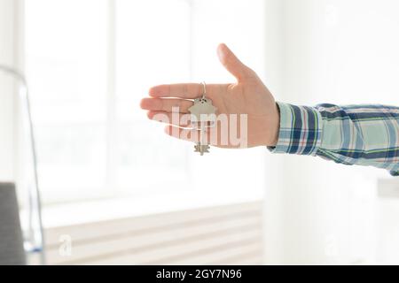 Tenir les clés de la maison sur le porte-clés en forme de maison dans une nouvelle maison.Concept de prêt hypothécaire et de prêt immobilier Banque D'Images