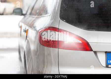 Détail du feu arrière d'une voiture moderne argentée à l'intérieur du lave-auto avec gouttes de savon. Gros plan d'un véhicule par l'arrière après nettoyage à l'eau. Banque D'Images