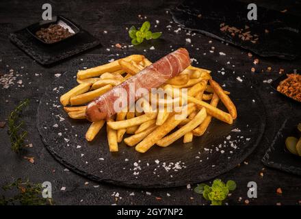 Saucisses grillées servies avec des frites roulées de bacon Banque D'Images