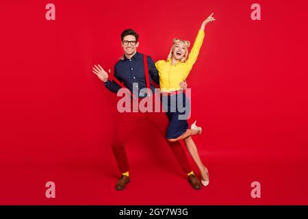 Vue sur toute la longueur du corps de la mode gai ecstatic Funky couple dansant en s'amusant isolé sur fond rouge vif Banque D'Images