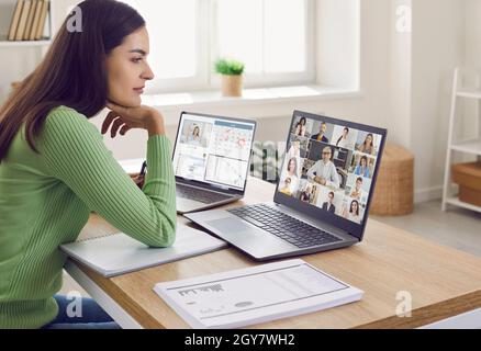 Une femme qui travaille à la maison est assise devant un ordinateur portable et a une réunion d'équipe en ligne Banque D'Images