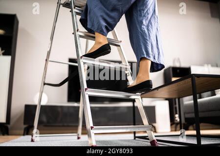 Sécurité de l'échelle. Femme grimpant escabeau dans des chaussures Banque D'Images