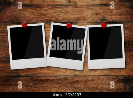 Gros plan trois cadres photo instantanés Polaroid vides fixés sur l'arrière-plan d'un mur en bois brun de grunge ancien, angle bas, vue latérale Banque D'Images