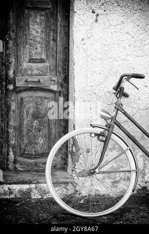 Vieilles portes et mur avec vélo d'époque, photo noir et blanc. Banque D'Images