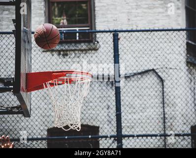Panier de basket-ball dans un terrain de jeu de quartier à New Yor. La balle rebondit sur le bord prêts à entrer. Banque D'Images