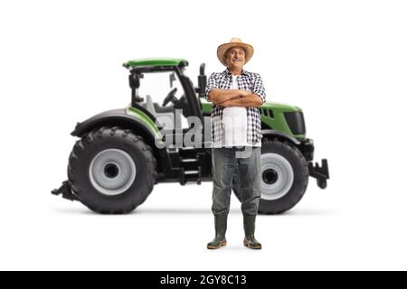 Portrait complet d'un agriculteur debout devant un tracteur vert isolé sur fond blanc Banque D'Images