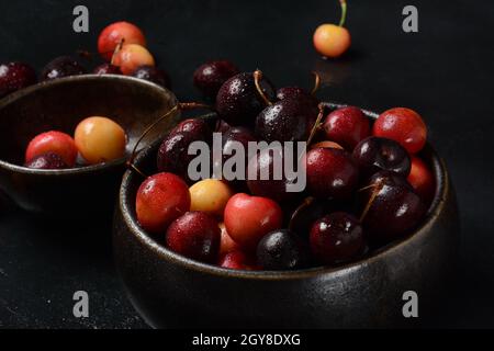 Cerises douces jaunes et rouges. Cerises fraîches mûres. Les cerises douces fraîches s'envasent dans des gouttes d'eau sur fond de pierre Banque D'Images