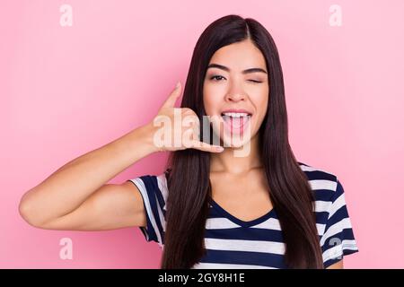 Photo de drôle douce jeune femme habillée de vêtements rayés souriant montrant le téléphone gestuelle isolé couleur rose arrière-plan Banque D'Images