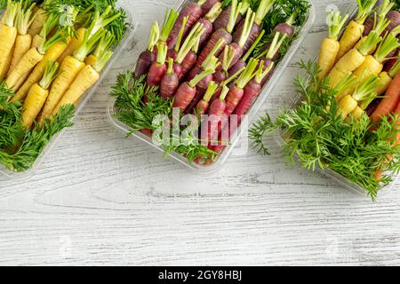 Mini carottes colorées fraîchement récoltées sur fond blanc en bois Banque D'Images