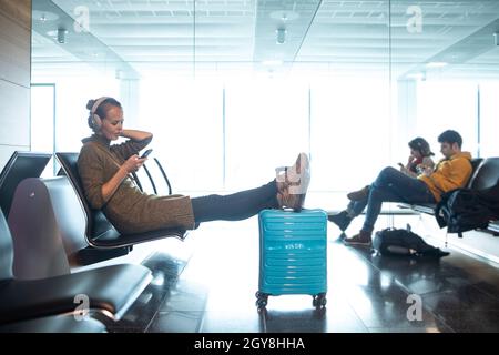 Une femme qui attend son heure d'embarquement à la porte d'un aéroport moderne à l'ère pré-covid (image couleur) Banque D'Images