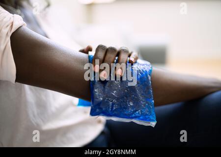 Femme utilisant un gel de glace sur le bras blessé Banque D'Images