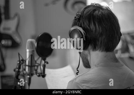 Chanteur en studio devant un grand diaphragme avec casque. Banque D'Images