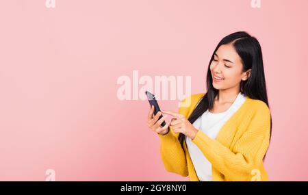 Joyeux portrait asiatique beau mignon jeune femme adolescent souriant excentré message texte sur smartphone mobile aime la communication en ligne isolé, s Banque D'Images