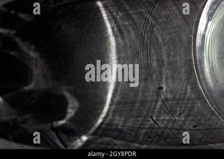 Arrière-plan abstrait gris foncé pour la conception, les réseaux sociaux, l'espace pour le texte.L'ombre d'un verre sur une table grise. Banque D'Images