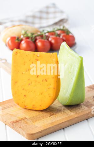 Bloc de fromage dur au piment et au wasabi sur planche à découper en bois. Banque D'Images