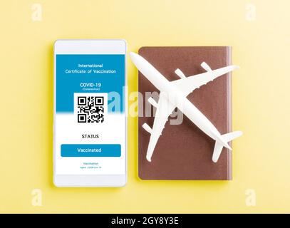 Modèle d'avion, passeport et carte d'immunité sont arrangés application sur smartphone sur fond jaune, Voyage concept pendant Covid-19 pandémie digita Banque D'Images