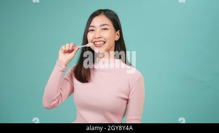 Asiatique jeune belle femme sourire brossage dents danse appréciant la musique, femme brosse dents chant chant chanson, danse et ont le plaisir isolé sur le backgro bleu Banque D'Images