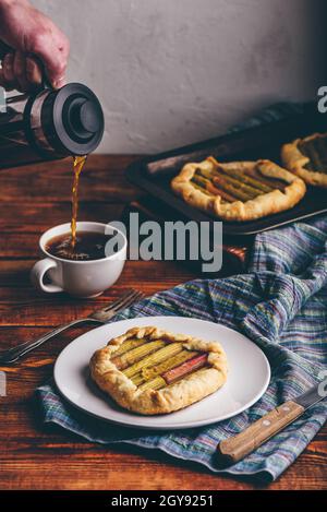 Mini-galette rhubarbe sur plaque blanche. À la main, avec une cafetière à piston Banque D'Images