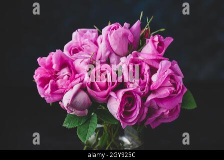 Bouquet de petites roses roses de jardin dans vase sur foncé arrière-plan Banque D'Images