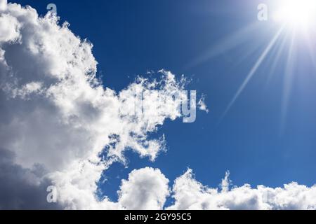 Beau ciel bleu avec des nuages de cumulus blancs et des rayons de soleil. Photographie en contre-jour. Banque D'Images