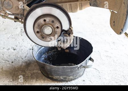 l'ancien liquide de frein est vidangé dans un bassin d'acier dans un atelier de voitures rurales (accent sur le nouveau segment de frein) Banque D'Images