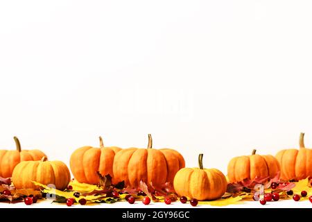 Feuilles d'érable multicolores, citrouilles et canneberges sur fond de nappe blanche.Composition d'automne avec espace de copie.Automne, automne, halloween, Thanksgiving Day concept. Banque D'Images