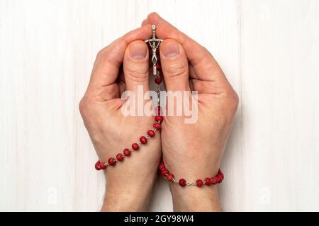 Mains pliées dans la prière avec un rosaire chrétien avec un croix Banque D'Images