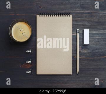 Photo d'un carnet de croquis kraft vierge, d'un crayon, d'une gomme et d'une tasse à café sur fond de table en bois.vue du dessus. Pose à plat. Banque D'Images