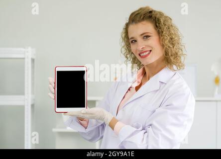 Jeune scientifique blond tenant un ordinateur de tablette à écran vide. Atmosphère de travail en laboratoire chimique. Banque D'Images