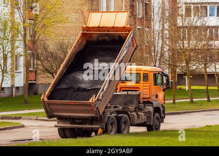 Benne basculante déchargeant l'asphalte frais de la carrosserie pendant les travaux de construction de routes Banque D'Images