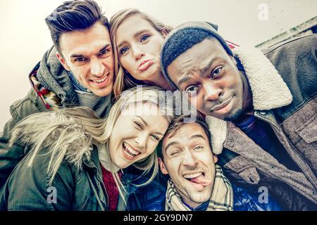 Les meilleurs amis qui prennent le selfie à l'extérieur sur les vêtements d'hiver d'automne - concept de jeunesse heureux avec des gens multiraciaux s'amusant ensemble Banque D'Images