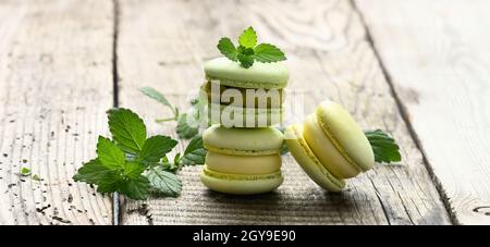 une pile de macarons de pistache cuits et de feuilles de menthe verte sur une table en bois gris Banque D'Images