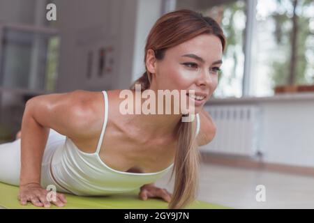 Jeune femme sur un tapis de yoga faisant la pose de la planche de dauphin Banque D'Images