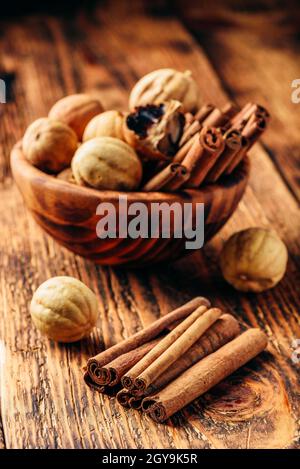 Les bâtons de cannelle et les limes à bol en bois sur table rustique Banque D'Images