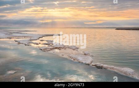 Le soleil du matin brille sur des formations de cristaux de sel, clair vert cyan eau calme près, paysage typique à la plage d'Ein Bokek, Israël. Banque D'Images