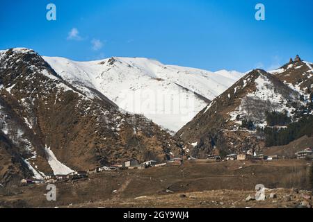 Début du printemps.Le village est dans les montagnes.Des chapeaux de neige sur les sommets des montagnes.Petit village au pied. Banque D'Images