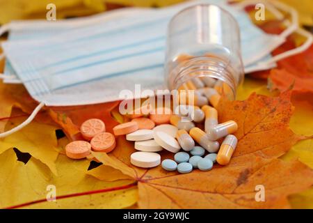 Pilules et masques protecteurs sur les feuilles d'érable d'automne.Concept de suppléments nutritionnels, vitamines pour l'immunité en saison de grippe et pandémie de coronavirus Banque D'Images