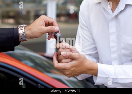 Un homme d'affaires en costume noir qui se charge de la clé de voiture pour le personnel de service de voiturier. Gros plan Banque D'Images