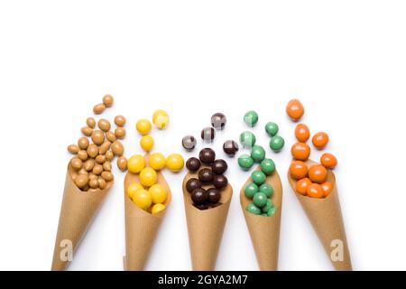 Différentes saveurs de pralines au chocolat dans des cônes en papier sur fond blanc. Banque D'Images