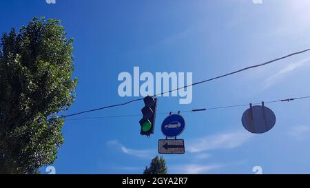 Feu de circulation et panneaux sur la rue à proximité avec un feu vert allumé. Banque D'Images