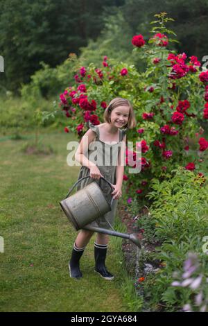 Une fille arrosoir des fleurs dans le jardin. Banque D'Images