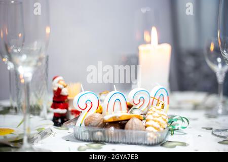 Table de Noël avec ustensiles et verres, table avec bougies allumées, dans une pièce sombre Banque D'Images