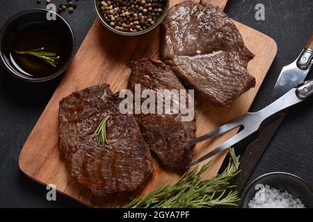 Steak de bœuf grillé juteux au romarin, viande frite, gros plan. Top Blade steaks sur bois Banque D'Images