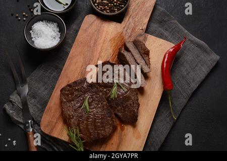 Steak de bœuf grillé juteux au romarin, viande frite, gros plan. Top Blade steaks sur bois Banque D'Images