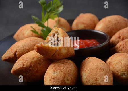 Kibbeh frits de viande de bœuf hachée mélangée à du bulgur, farcis avec de la viande hachée frite et des pignons de pin sur le plan de coupe, sur fond sombre Banque D'Images